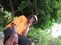 a man sitting on a rock and talking on a cell phone